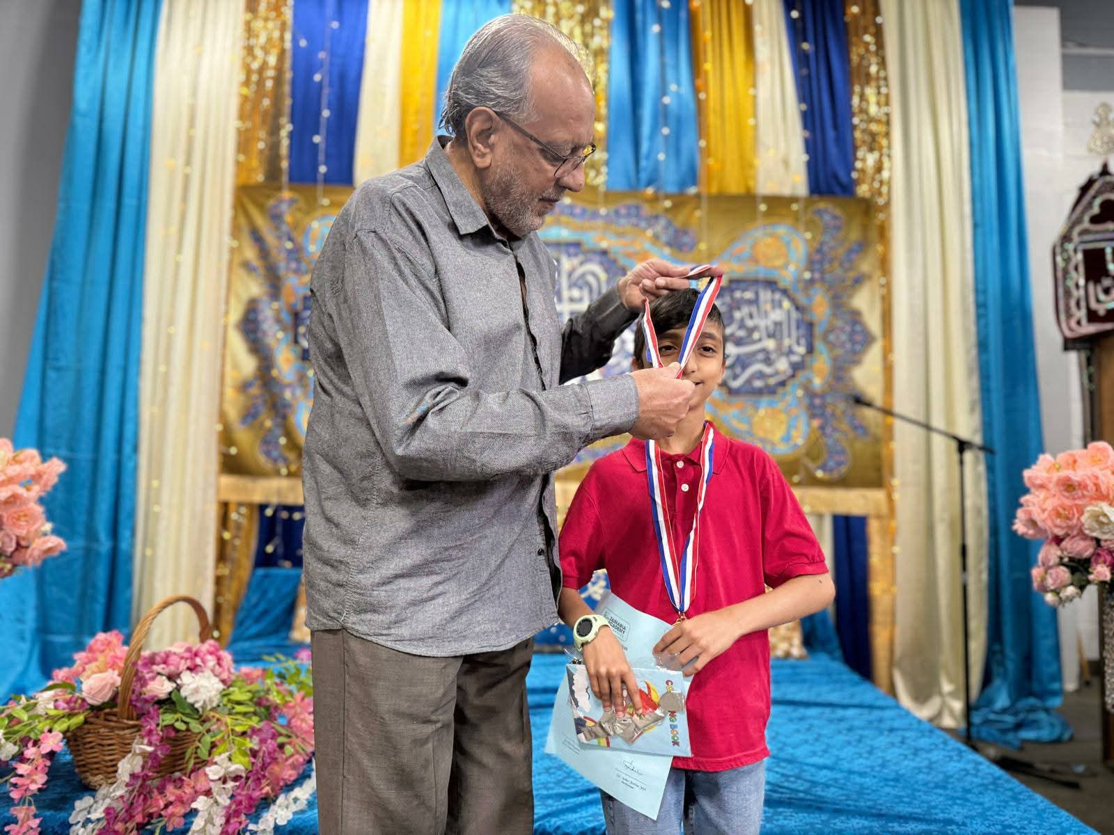 A student being presented with a medal at a Zainabia Academy ceremony