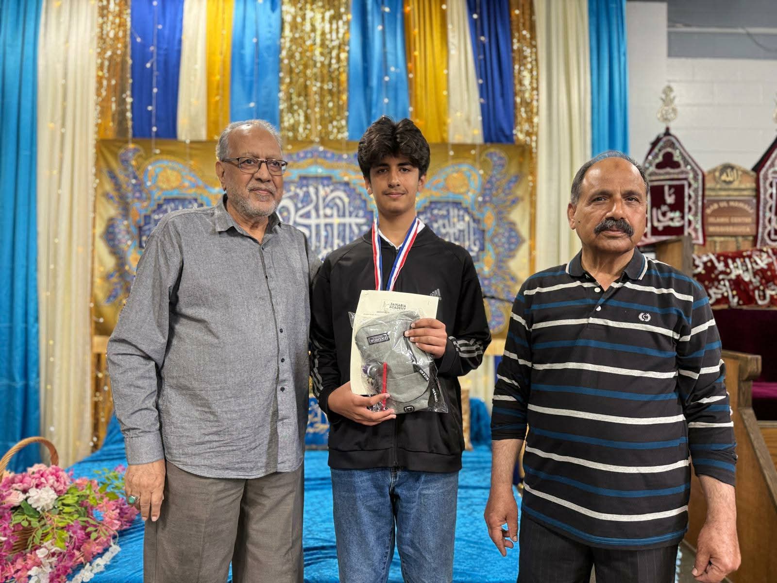 A student receiving his award with academy elders at the annual day