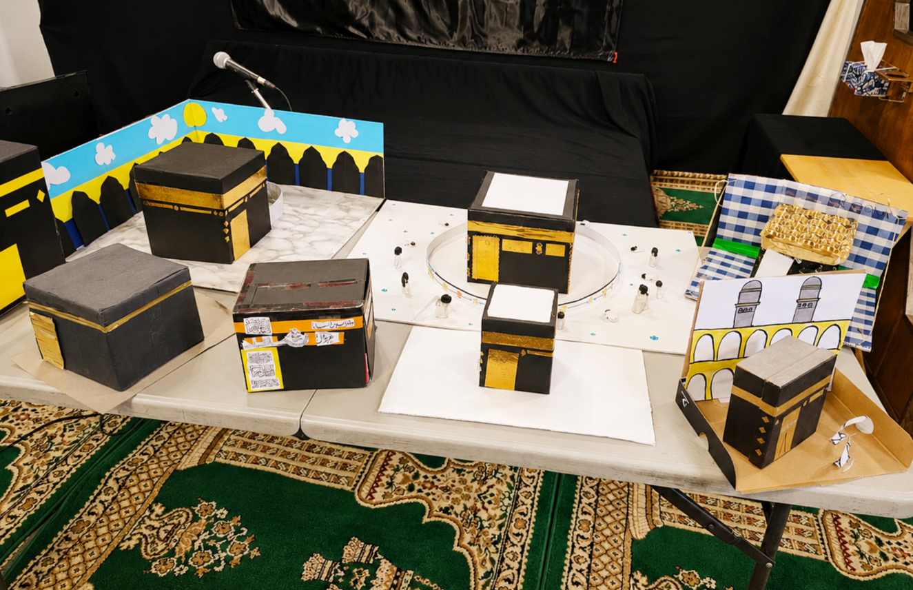 Student-made Hajj and Kaaba models displayed on a table
